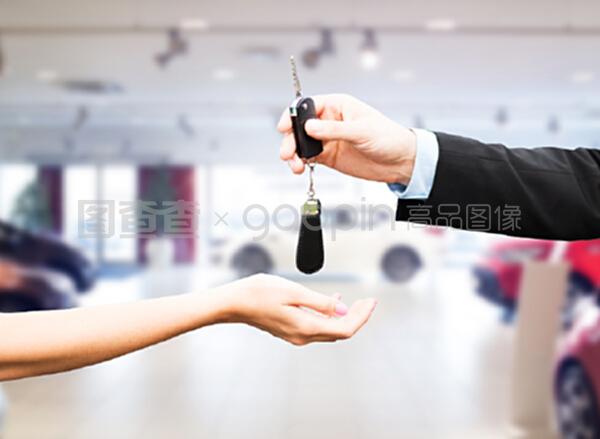 汽車業務、汽車銷售、運輸、人員和所有權概念----汽車銷售人員在汽車展示背景下為新老板或新客戶提供鑰匙